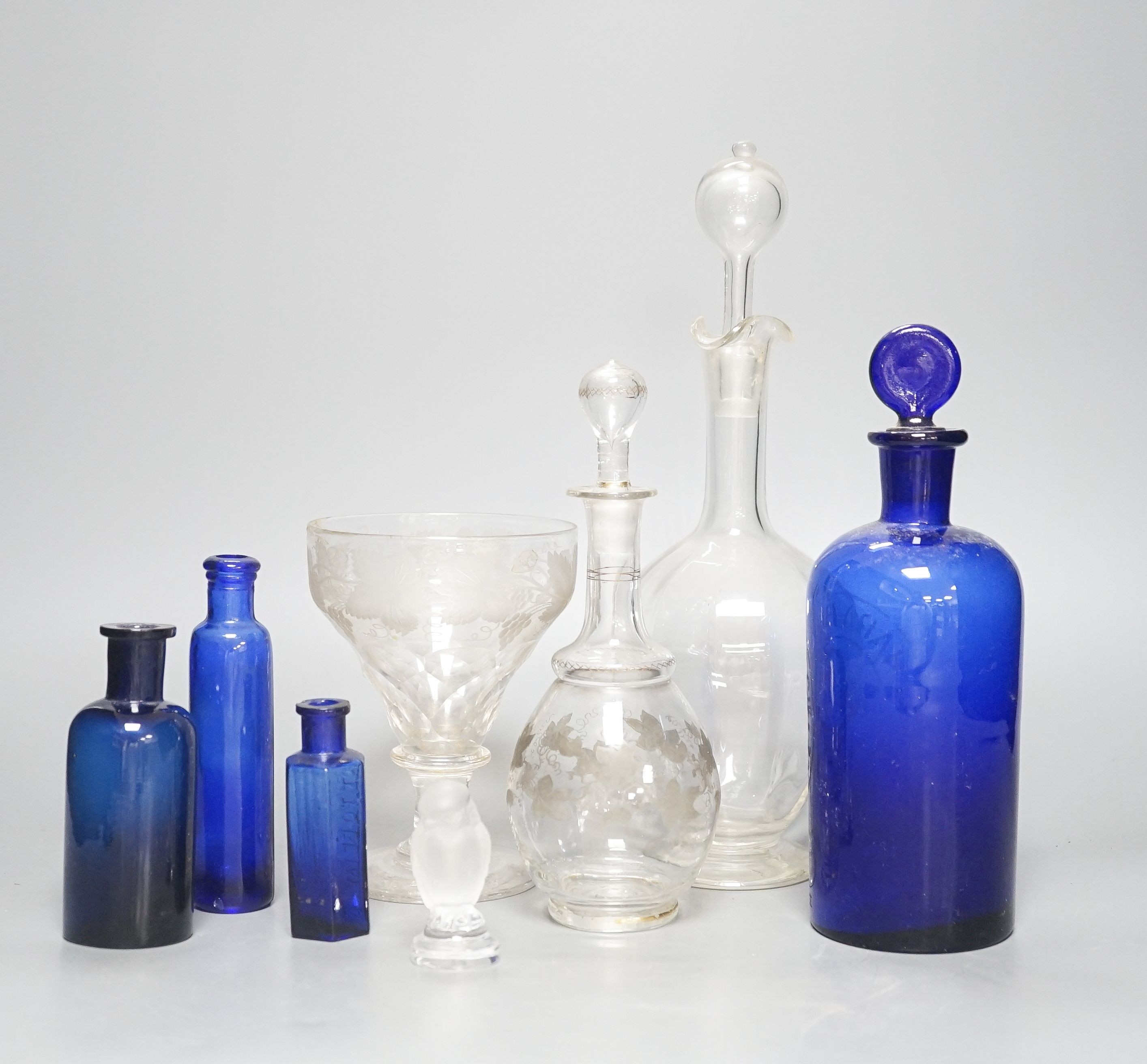 A Lalique frosted glass bird, etched Wedgwood ‘plant a tree ‘73’ glass, other etched glasses, decanters and blue glass pharmacy bottles